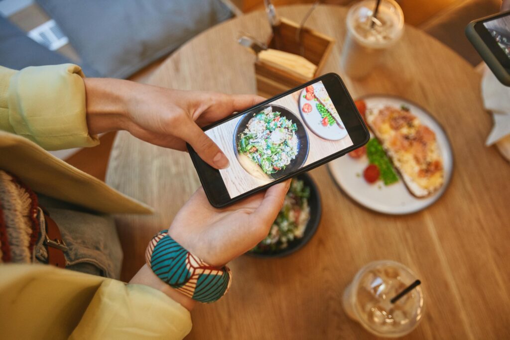 a person holding a phone with food on it