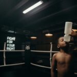 a boy drinking from a bottle in a boxing ring