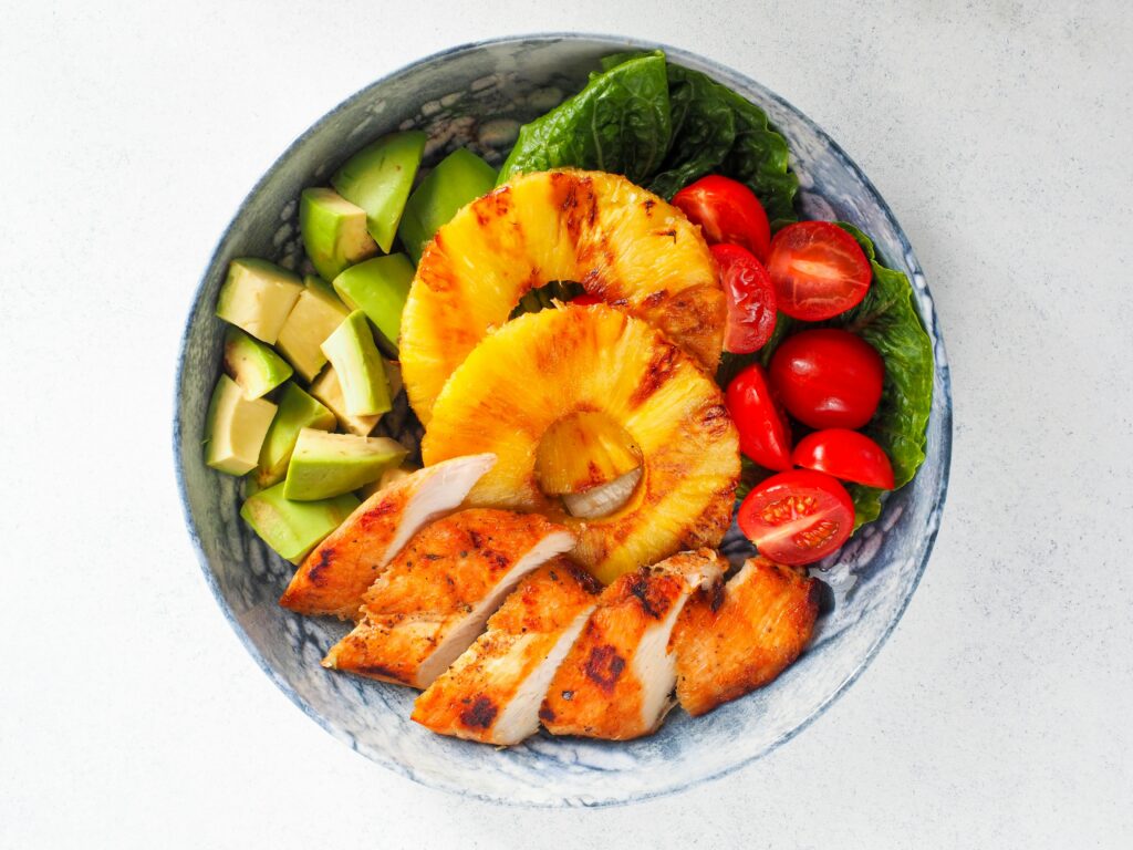 a bowl of food with chicken and pineapple slices